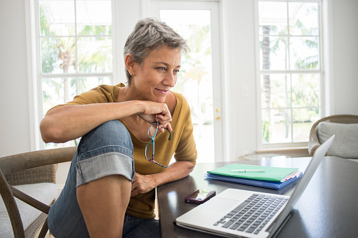 Woman using laptop in living room wiring money overseas on a laptop